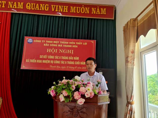 A person standing behind a podium with flowers in front of a sign

Description automatically generated with low confidence